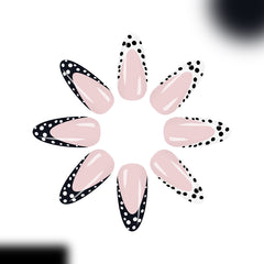Trendy glossy almond-shaped press-on nails with black and white dotted French tip details displayed on female hands.