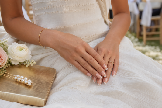 Warm nude French almond press-on nails styled with an artisan white wedding guest dress