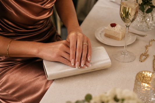 Nude French almond press-on nails styled with a bronze wedding guest dress