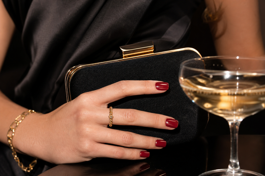 Glossy cherry red short square press-on nails with a black clutch at a cocktail party