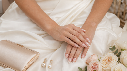 Warm nude French almond press-on nails styled with an eggshell white wedding guest dress