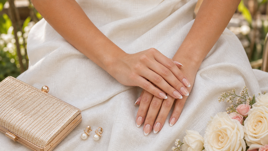 Warm nude French almond press-on nails styled with a linen white wedding guest dress