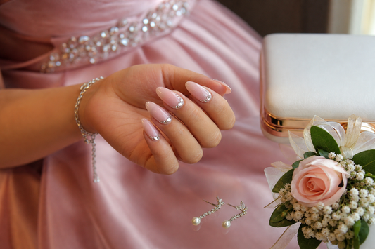 Soft pink rhinestone almond press-on nails styled with a pastel prom dress