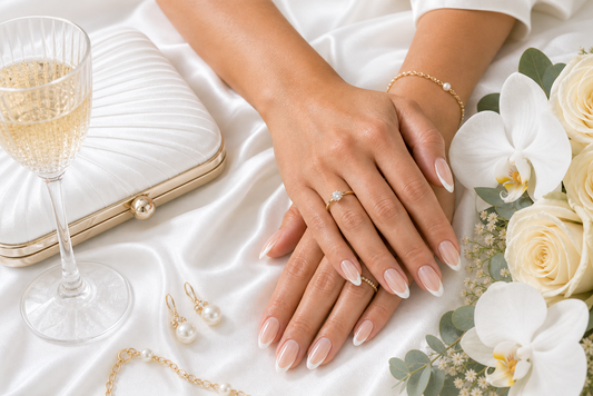Warm nude French almond press-on nails styled with a pure white wedding guest dress
