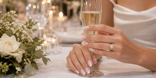 Glazed bridal press-on nails holding champagne at a wedding reception