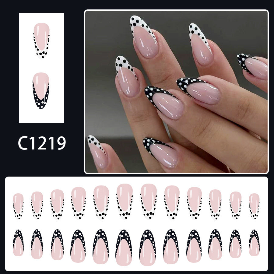 Elegant nude almond nails with glossy finish and black French tip design decorated with white polka dots.