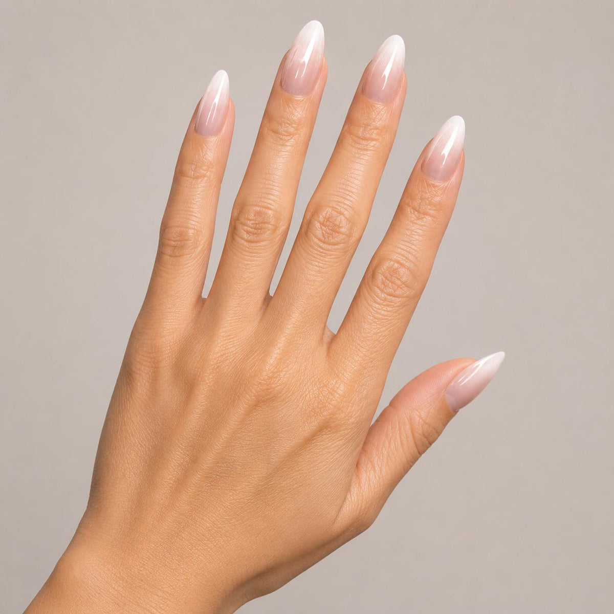 Hand with long, pointed nails painted in a light color against a neutral background
