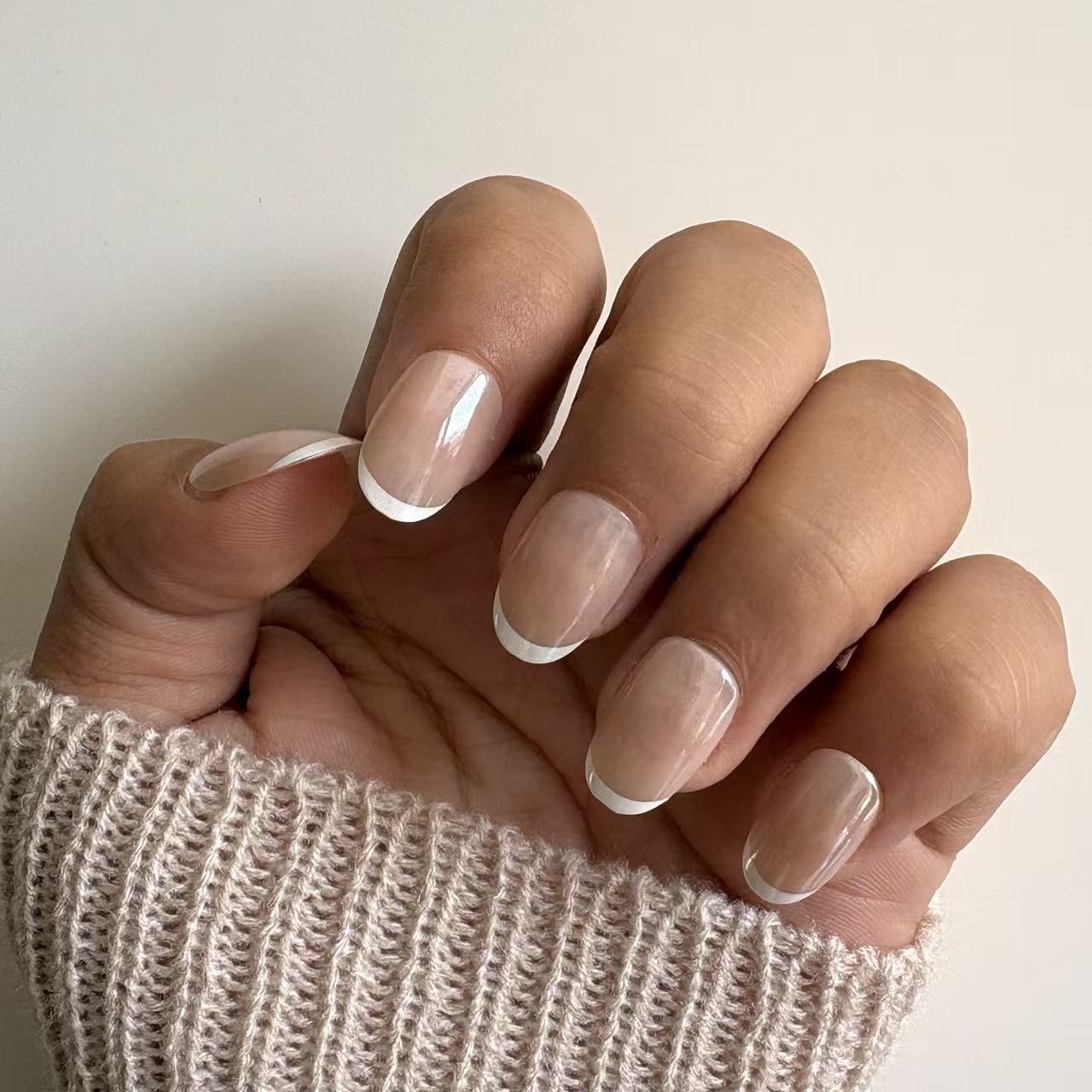 Elegant nude glossy press-on nails with white French manicure tips and natural short square nail shape.