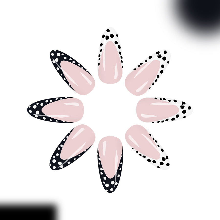 Trendy glossy almond-shaped press-on nails with black and white dotted French tip details displayed on female hands.